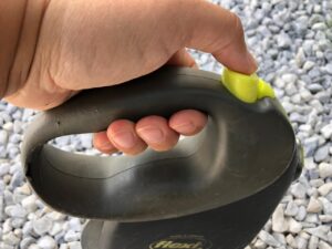 Blick von der Seite auf eine Flexileine mit dem Daumen auf der Bremse