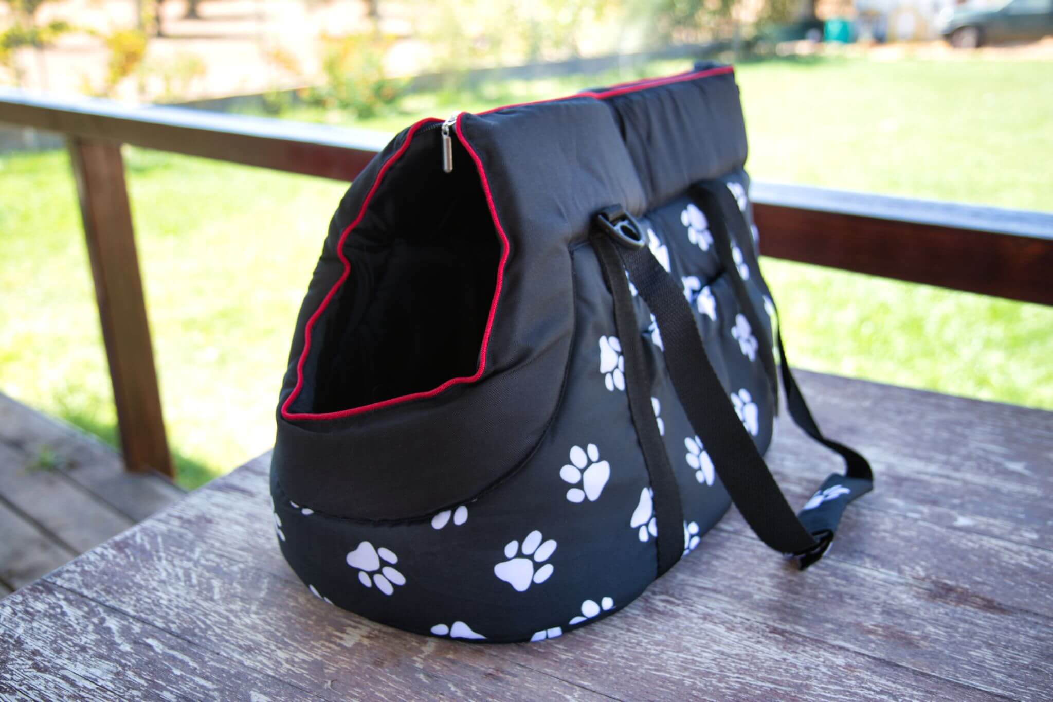 Unsere getestete Hundetragetasche von Hobbydog ist aus Polyester, schwarz mit weißem Pfotendruck und roten Nähten.