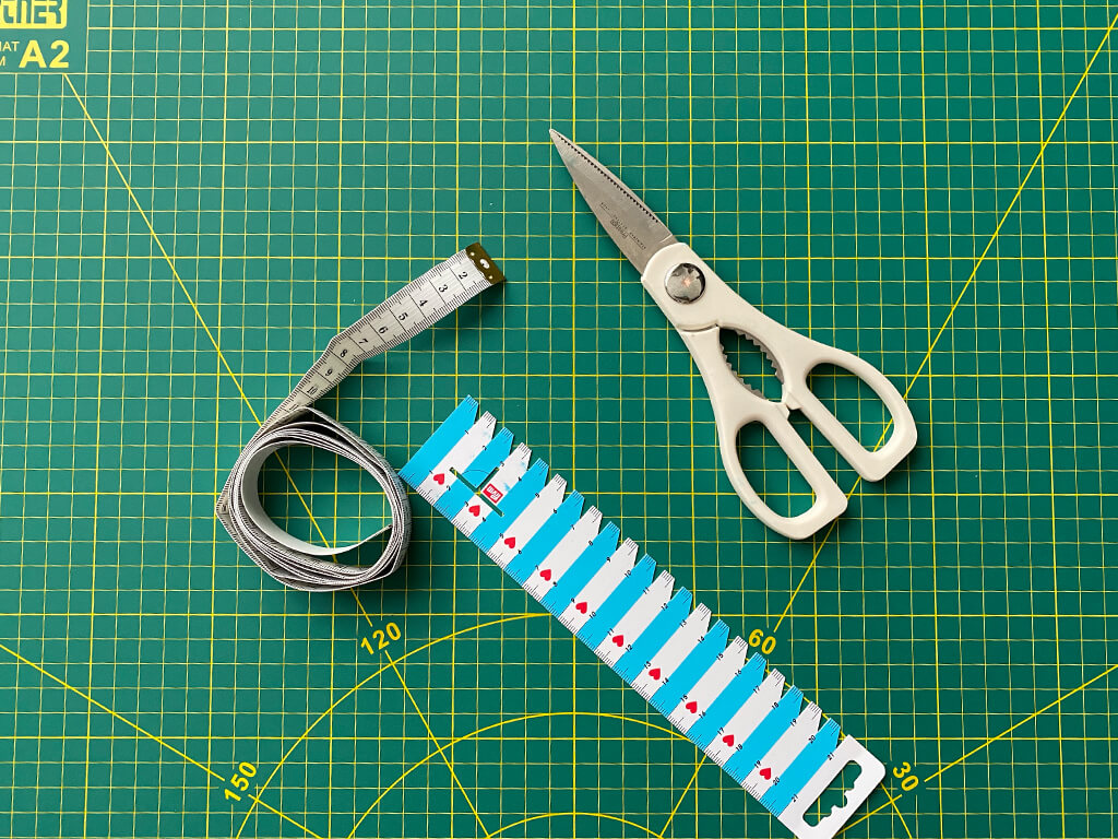 Maßband, Handmaß und Schere auf grünem Untergrund